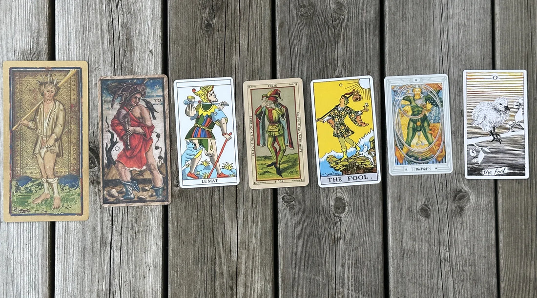 Narren (The Fool) från sju olika tarotlekar uppradade kronologiskt på en grå träyta – från Visconti-Sforza på 1400-talet till The Wild Unknown i modern tid.