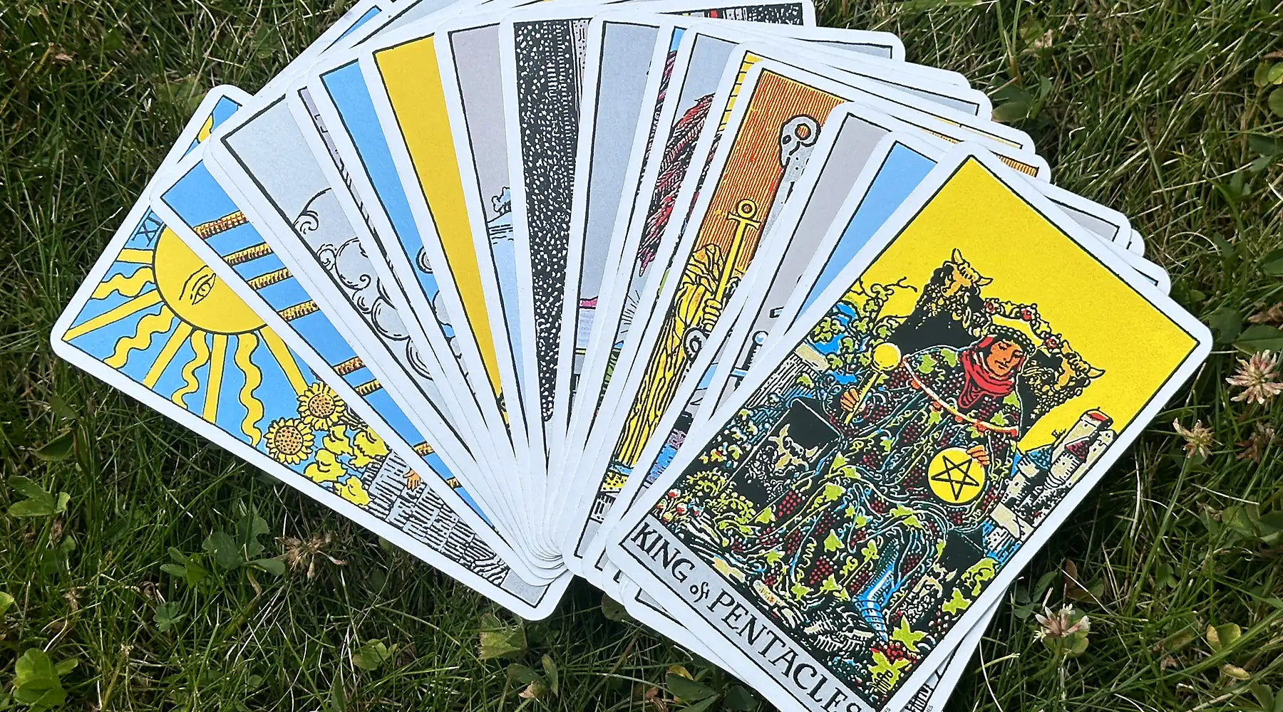 En tarotlek i Rider-Waite-Smith-stil utlagd som en solfjäder på gräs, med kung i pentagramlängst fram.