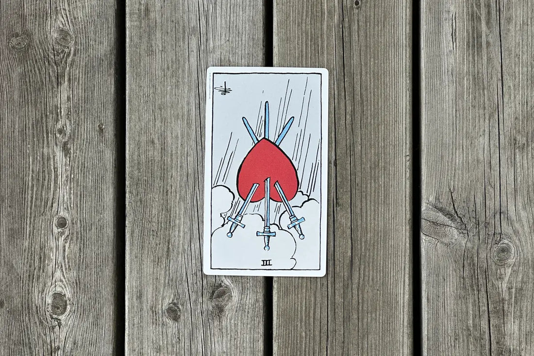 Tre i svärd som omvänt tarotkort mot en träbakgrund