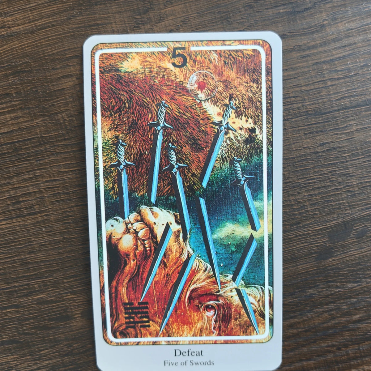 Kortet Defeat Five of Swords ur Haindl Tarot med fem blå svärd mot en eldröd, målad bakgrund