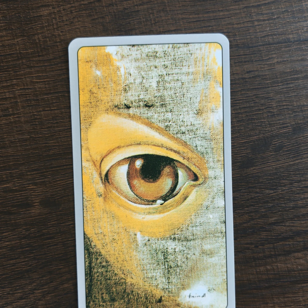 Baksidan på korten i Haindl Tarot med ett stort brunt öga målat i gult och grått på ljusgrå kant