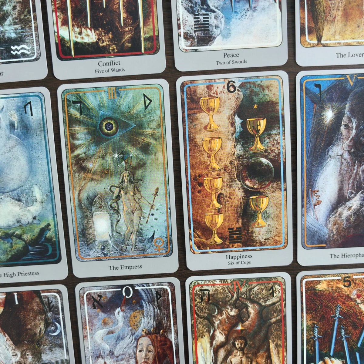 Kort ur Haindl Tarot i rutnät på ett träbord, bland annat The Empress, Happiness Six of Cups och The Lovers