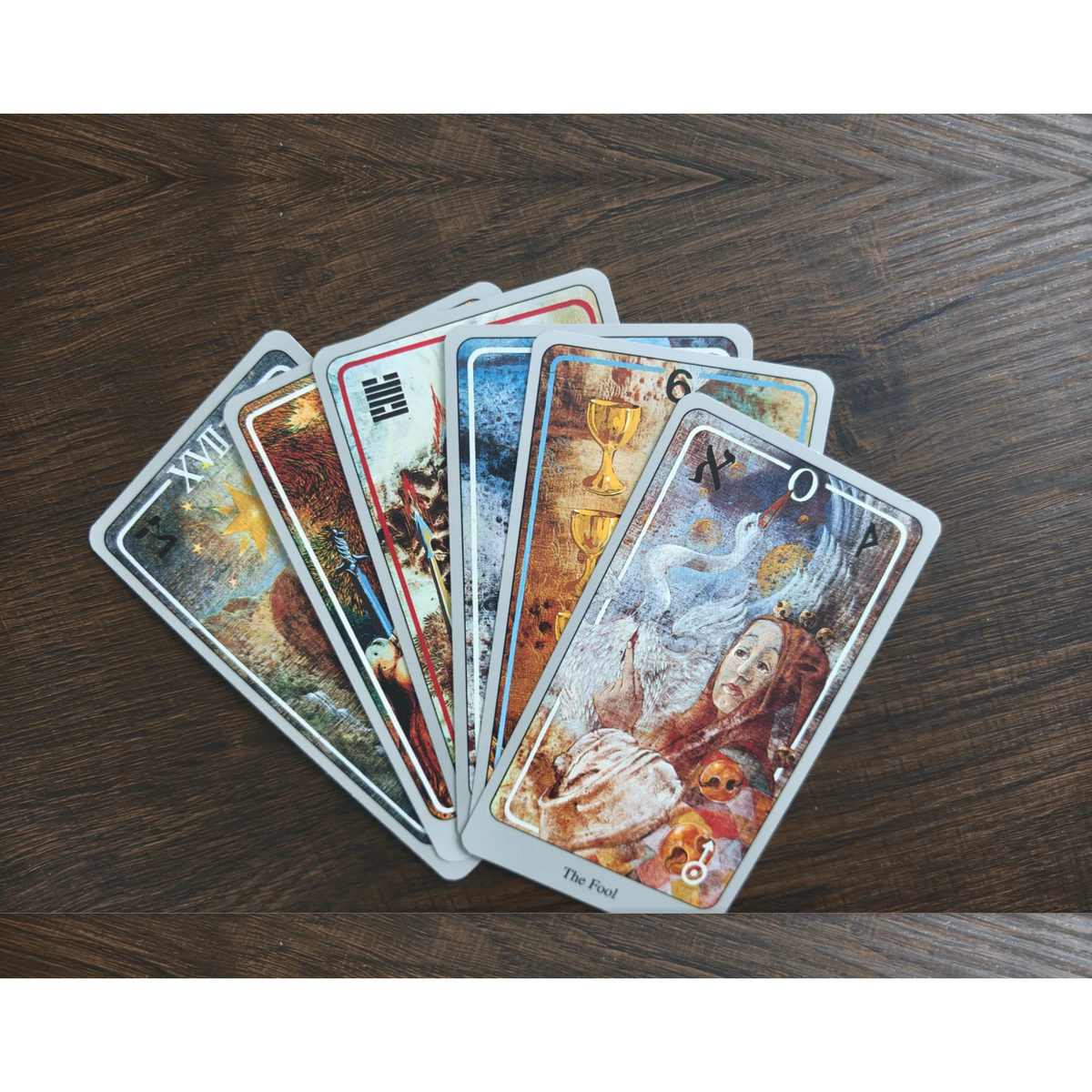 Sex kort ur Haindl Tarot utlagda som en solfjäder på ett träbord, med The Fool överst