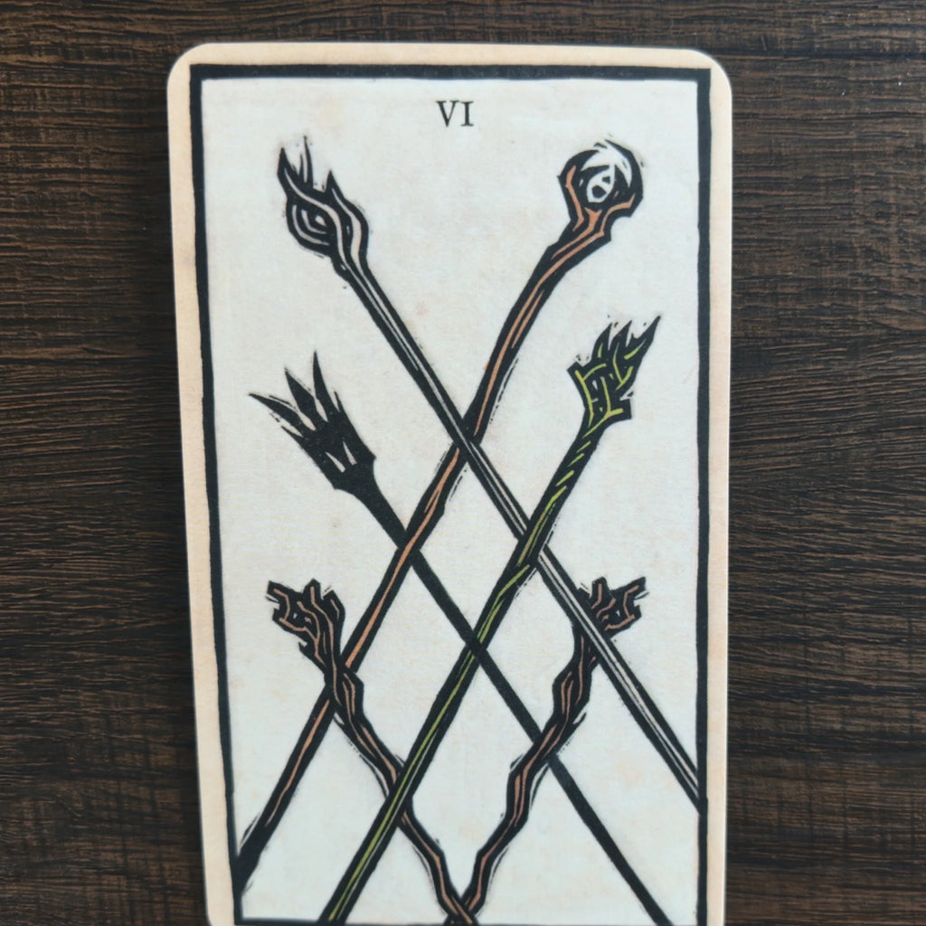 Ett kort märkt VI ur The Lord of the Rings Tarot med sex korsade stavar i svart, orange och grönt på ljus bakgrund
