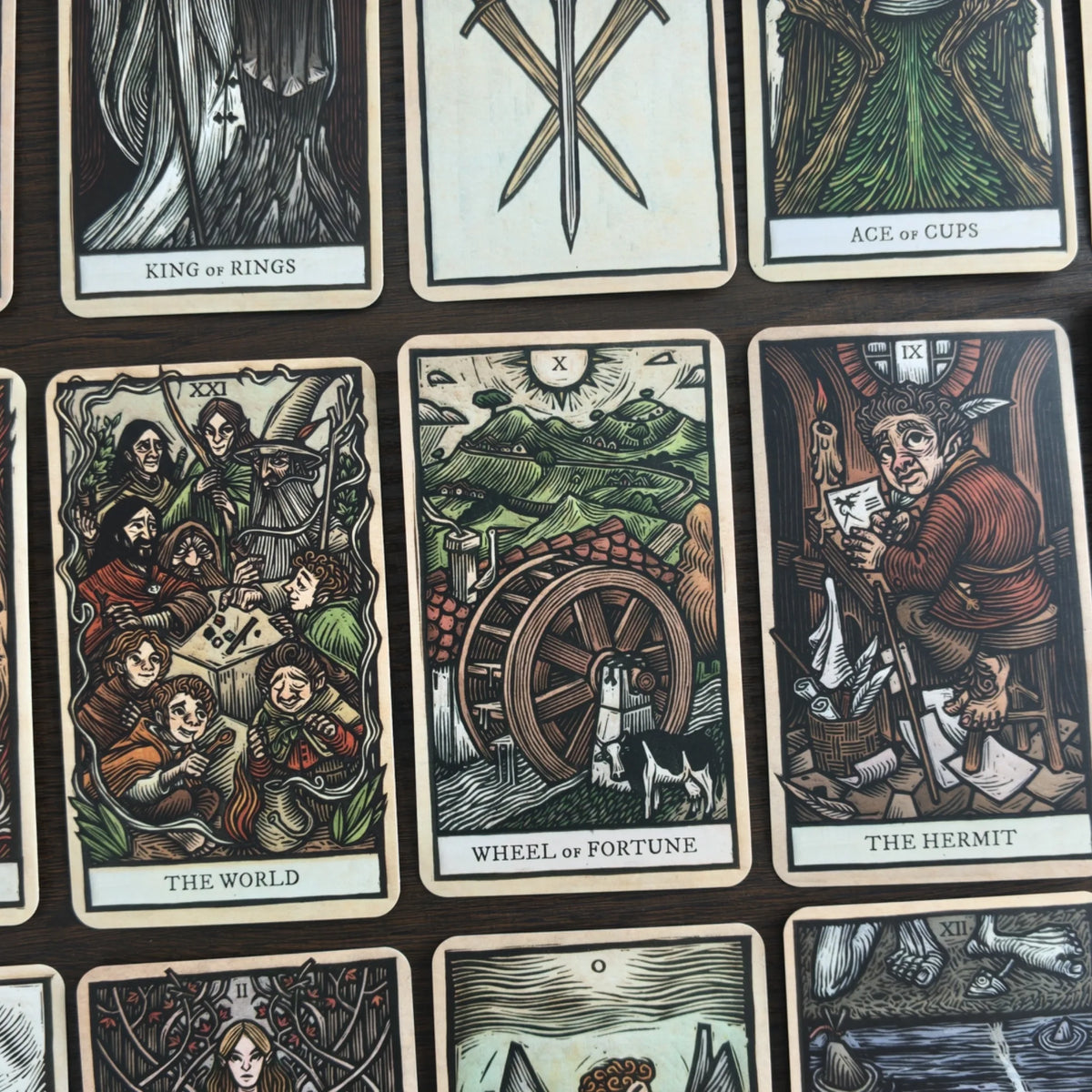 Kort ur The Lord of the Rings Tarot i rutnät i träsnittsstil, bland annat The World, Wheel of Fortune och The Hermit