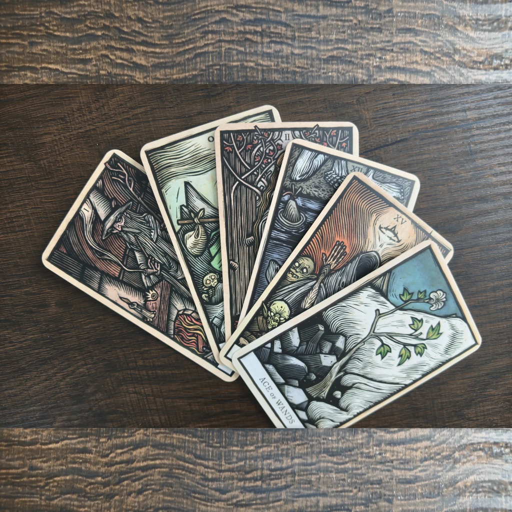 Sex kort ur The Lord of the Rings Tarot utlagda som en solfjäder på ett mörkt träbord, med Ace of Wands överst