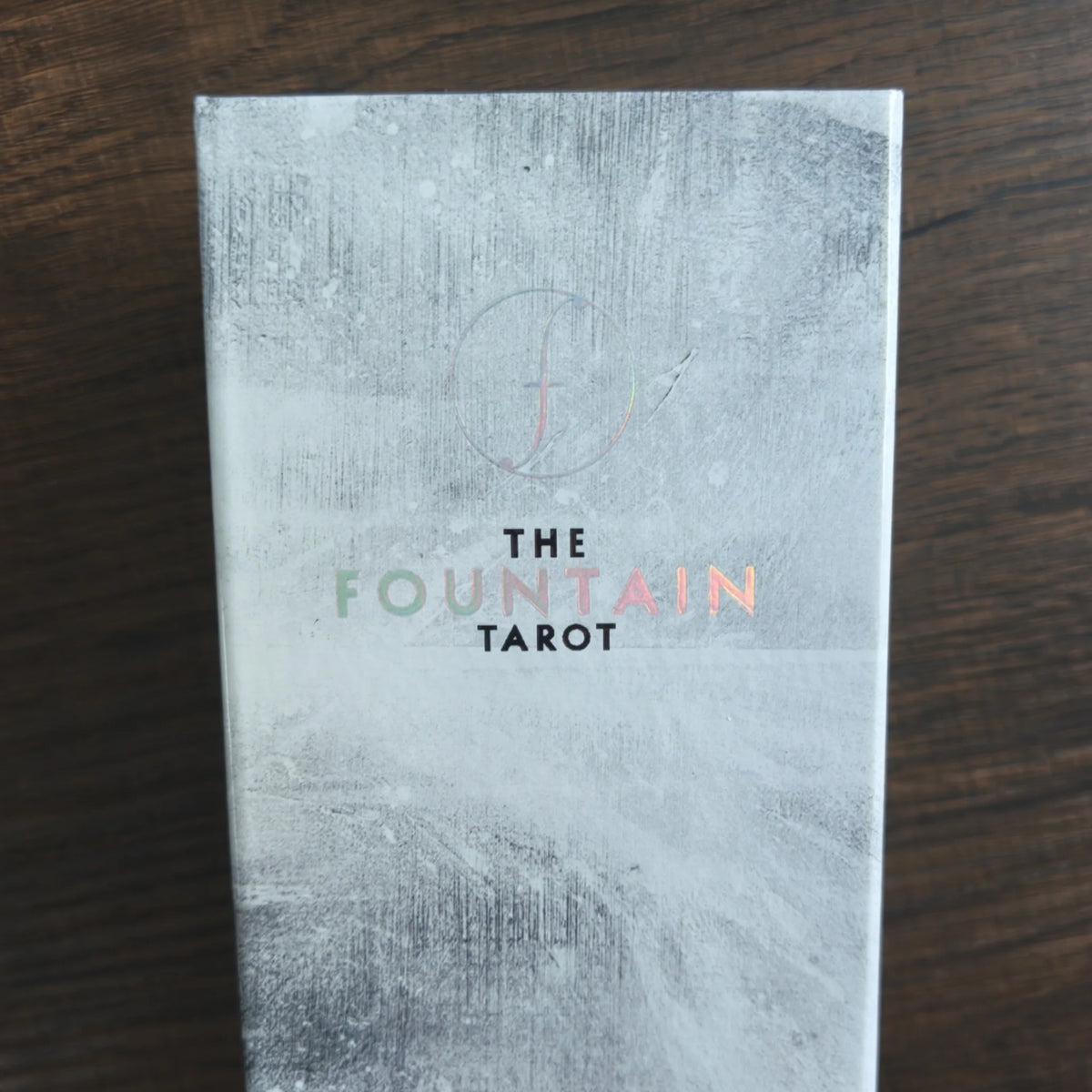 Asken till The Fountain Tarot framifrån i ljusgrått marmorliknande mönster med titeln i skimrande regnbågsfolie
