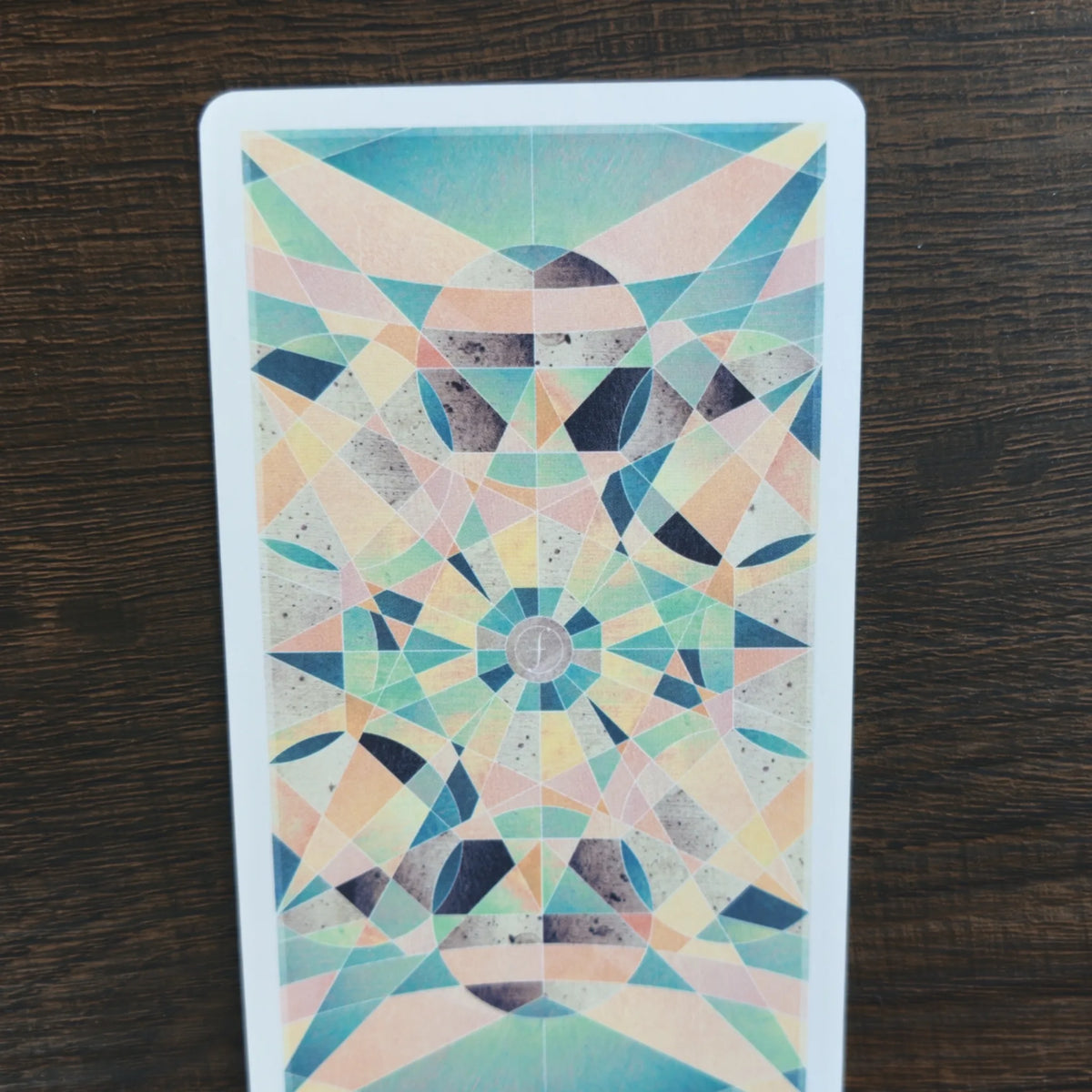 Baksidan på korten i The Fountain Tarot med ett geometriskt kalejdoskopmönster i turkos, persika och grått